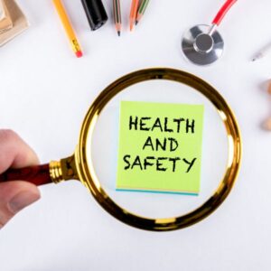 Magnifying glass looking at a sticky note that says "Health and Safety".